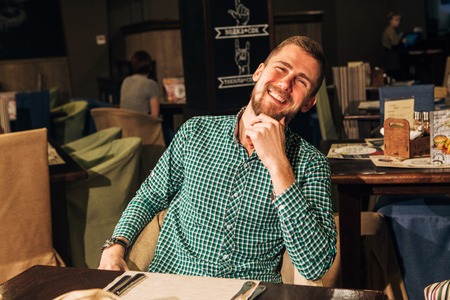 young man in restaurant smiling,the man smiles at the frame sitting in the restaurantの写真素材