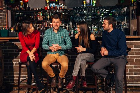 Two happy smiling young couples with champagne at celebration, party or romantic date at clubの写真素材