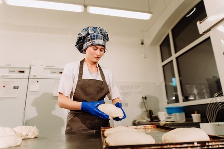 a Baker prepares dough for bread in the bakeryの写真素材