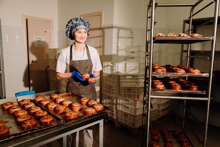 Baker smiling at camera holding rack of rolls in a commercial kitchenの写真素材