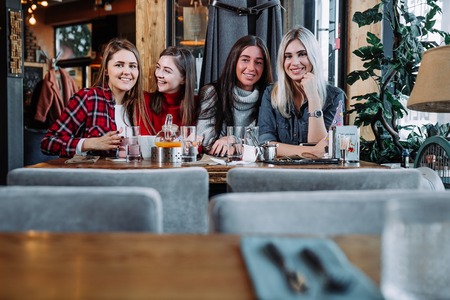 four friends in the cafe look at the camera and laughの写真素材