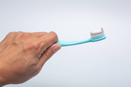 Hand holding toothbrush with toopasteの写真素材