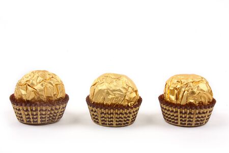 Sweet chocolate bonbon in golden foil on white background の写真素材