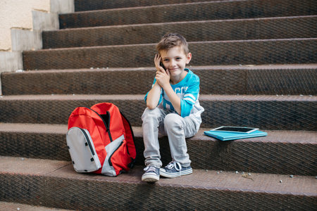 Smiling child making a phone call outside a schoolの写真素材