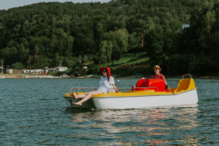 Couple in love enjoying boating in the lake. Portrait of young man and woman pedal boating on the river.の写真素材