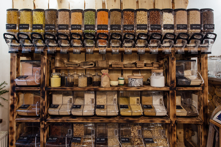 Front view of variety of seeds and nuts displayed in grocery store. Zero waste shopping - shelf with glass jars full of dry food in organic shop.の写真素材