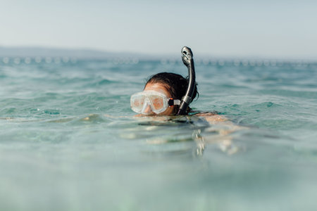 Female swimmer learning to snorkel. Snorkeling - woman wearing diving mask and snorkel swimming in...