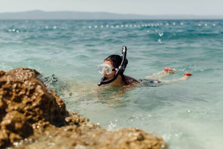 Female diver learning to dive at seashore. Woman wearing diving mask and snorkel snorkeling in sea on hot sunny day.の写真素材