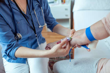 Close up of Nurse Taking Blood Samples from Elderly Patient. Female Caregiver Obtaining Blood Samples From Patients Vein.の写真素材