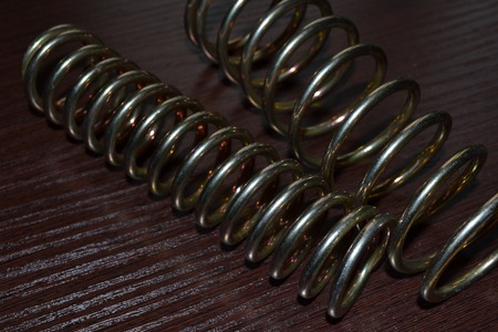 Closeup of shiny galvanized coiled springs on a dark wooden textured backgroundの写真素材