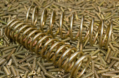 Two shiny golden coiled springs on a beautiful background of many small bright helical springs to...