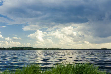 Dark landscape with forest lake before stormy rainの写真素材