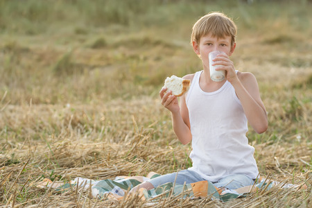 Teenage farmer boy tasting a fresh milk and breadの写真素材