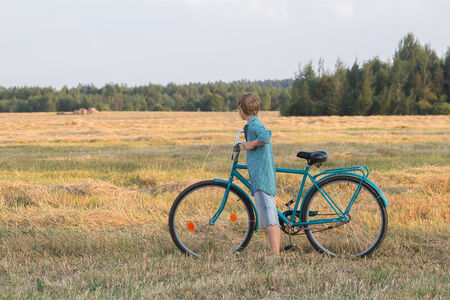 Teenager boy holding a bicycle in farm fieldの写真素材