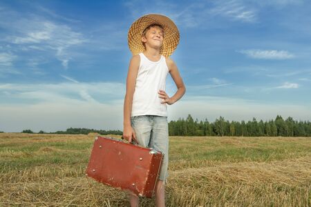 Laughing teenage hitchhiker in countryside field near roadの写真素材