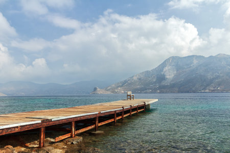 Sea beach coastline with wooden pier on autumn Greek Dodecanese Telendos islandの写真素材