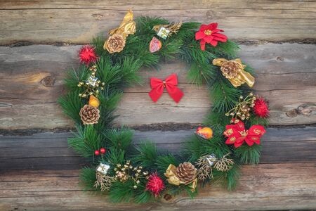 Outdoor Christmas conifer wreath at old grey log cabin wall backgroundの写真素材