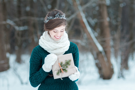 Smiling young woman holding Christmas gift in handsの写真素材