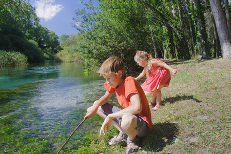 Siblings summer recreation activity outdoor game on Italian Tirino river bank in sunny dayの写真素材