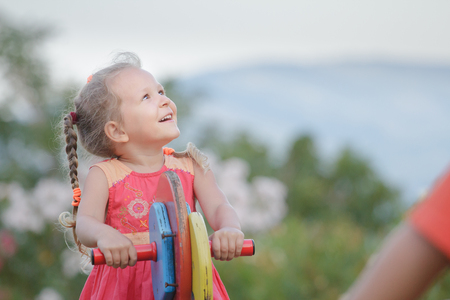 Recreational activity of little kid girl swinging on wooden playground equipment summer outdoorsの写真素材