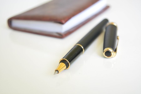 A pen and notebook on white backgroundの写真素材