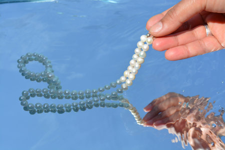 Pearls and hands reflected in pure water