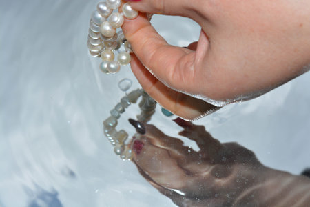Pearls and hands reflected in pure waterの写真素材