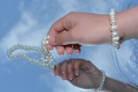 Pearls and hands reflected in pure waterの写真素材