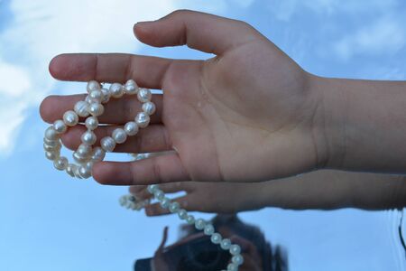 Pearls and hands reflected in pure waterの写真素材