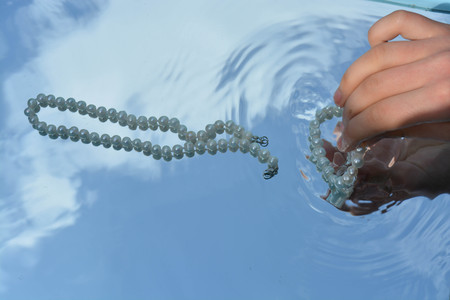 Pearls and hands reflected in pure waterの写真素材
