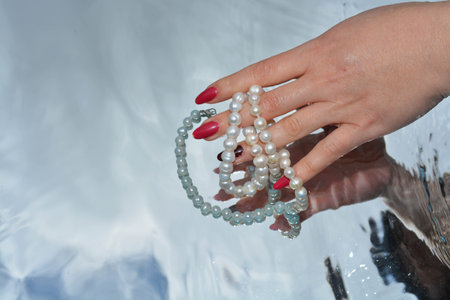 Pearls and hands reflected in pure water