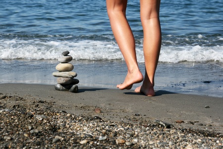 Female walking on the beach around a pile od stoned arranged as a Zen symbolの写真素材
