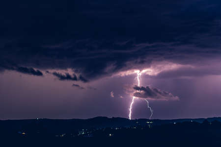 Night landscape on a background of thunderstorms. Rural silhouette and clouds with lightning flashesの写真素材