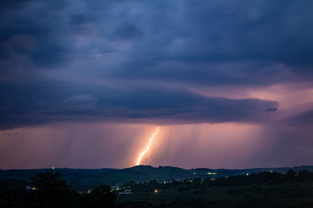 Night landscape on a background of thunderstorms. Rural silhouette and clouds with lightning flashes