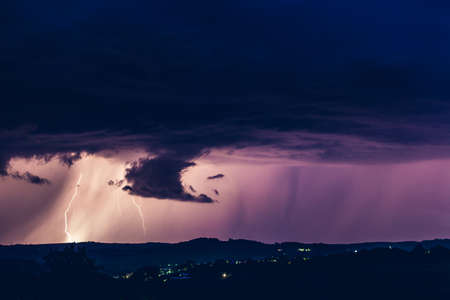 Night landscape on a background of thunderstorms. Rural silhouette and clouds with lightning flashesの写真素材