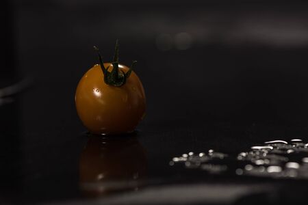 Yellow tomatoes on black background ,water drops ,closeup ,  mirrorの写真素材