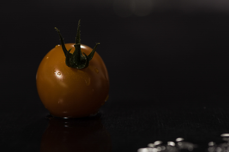 Yellow tomatoes on black background ,water drops ,closeup ,  mirrorの写真素材