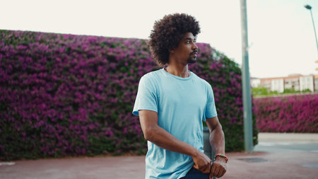 young African American man going on city street on background wall covered with purple flowers. lifestyle conceptの写真素材