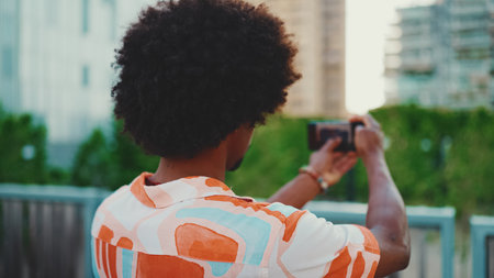 Close-up of young African American wearing shirt shooting use smartphone stands on bridge on urban street background. lifestyle conceptの写真素材