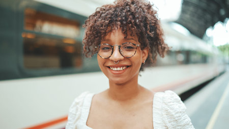 close-up portrait of a young woman in glasses stands on the platform next to the train and smiles