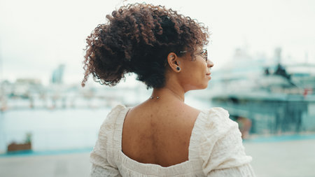 Closeup of a young woman in glasses stands in the seaport and looks at the ships.の写真素材