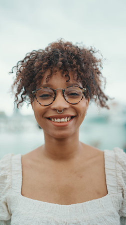 Closeup portrait of a young woman in glasses stands in the seaport and poses for the camera