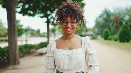 Smiling young woman walking in the park. Girl goes in the city park and looks aroundの写真素材