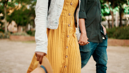 Closeup, man and woman walk holding hands. Close-up of the hands of a young interracial couple