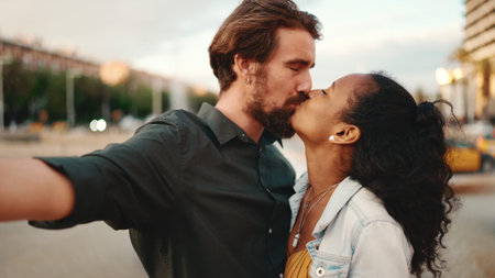 Closeup of smiling interracial couple taking a selfie on fountain background. Close-up, man and woman video chatting using a mobile phoneの写真素材