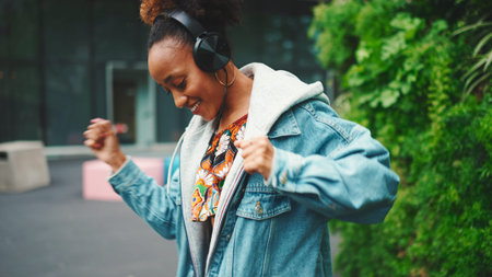 Closeup, smiling African girl wearing denim jacket, in crop top with national pattern walks in city...