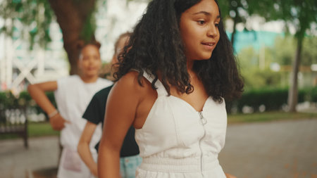 Three girls friends pre-teenage dance and play in the city park backgroundの写真素材