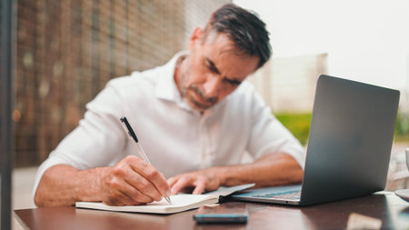 Mature businessman with neat beard wearing white shirt user on laptop pc computer sit at cafe...