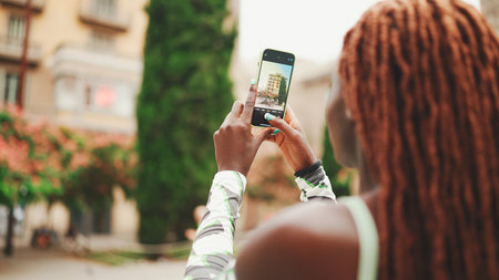 Close-up of beautiful woman with African braids takes photo on mobile phone.の写真素材
