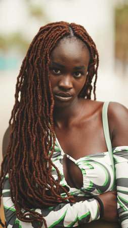 Close up portrait of gorgeous woman with African braids wearing walks down the street.
